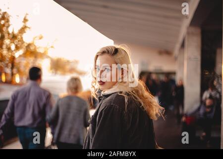 Ragazza adolescente guardando indietro alla fotocamera camminando sulla stazione della metropolitana Foto Stock