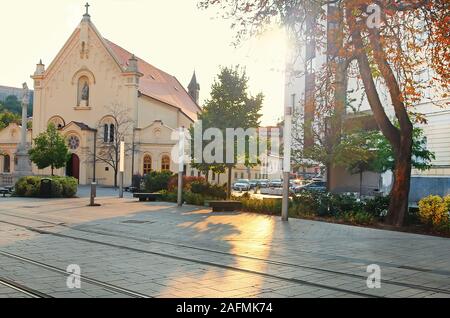 Santo Stefano chiesa di sera, Bratislava, Slovacchia. Il giallo di riflessi e ombre sul marciapiede dalla luce solare Foto Stock