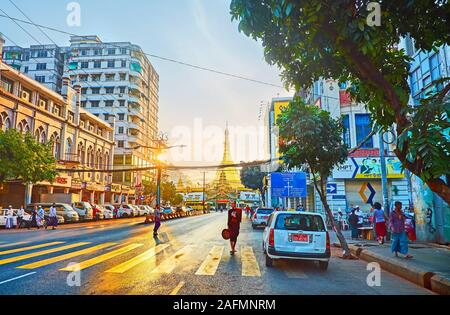 YANGON, MYANMAR - 17 febbraio 2018: l'alba a piedi lungo la trafficata Maha Bandula strada con vista su crosswalk nella luce solare e Sule Paya su backgrou Foto Stock