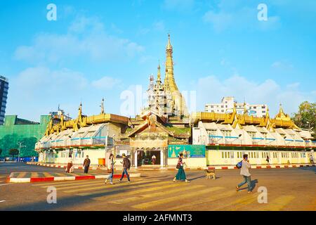 YANGON, MYANMAR - 17 febbraio 2018: persone attraversano la strada di Sule Pagoda, circondato da mercato coperto, il 17 febbraio a Yangon. Foto Stock