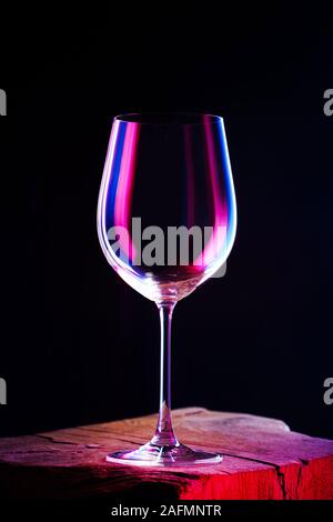 Bicchiere vuoto per un vino sul tavolo di legno e uno sfondo scuro Foto Stock