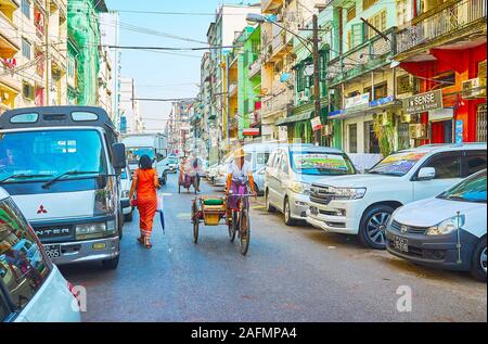 YANGON, MYANMAR - 17 febbraio 2018: l'equitazione lentamente in rickshaw, cercando i clienti in strada residenziale di Chinatown, il 17 febbraio di Yangon Foto Stock