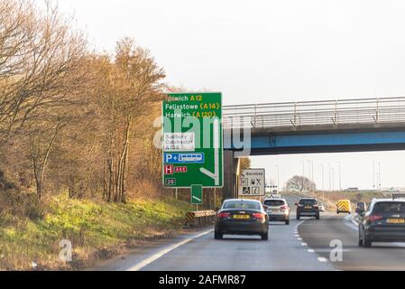 Cartello stradale le direzioni di Ipswich, Felixstowe, Harwich, Sudbury, Colchester veicoli con guida su un tratto di un duello12 carreggiata, Essex, UK. Foto Stock