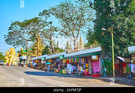 YANGON, MYANMAR - 17 febbraio 2018: le bancarelle del mercato tradizionale in Ar Zar Ni street con una vista su Chinthe leoni della Porta Nord della Shwedagon Foto Stock