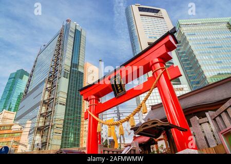 Tradizione e modernità in Giappone. Vista di Shimbashi-Shiodome moderni grattacieli dietro la porta rossa di Hibiya Santuario nel centro cittadino Foto Stock