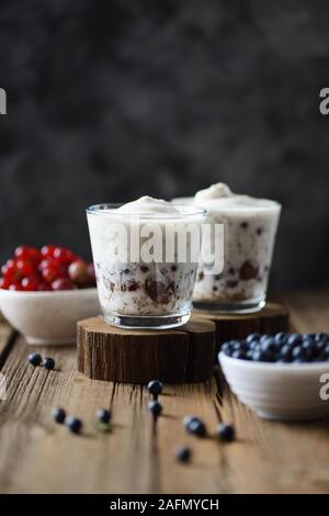 Snack sani con superfoods. Budino di Chia con crema di noce di cocco, mirtilli e ribes rosso su sfondo scuro spazio copia Foto Stock