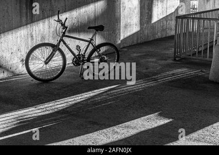 Un bycycle lasciato incustodito nel garage parcheggio con luce e ombre Foto Stock