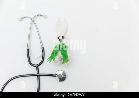 Semplicemente minimal design toy bunny e apparecchiature di medicina uno stetoscopio isolati su sfondo bianco. La cura della salute dei bambini concetto medico. Pediatra simbolo. Flat Top laici visualizza lo spazio di copia Foto Stock