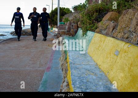 Pattuglia di polizia la litoranea pedonale marciapiede lungo il foreshore di Fishhoek sull Africa del sud della Penisola del Capo popolare con i turisti Foto Stock