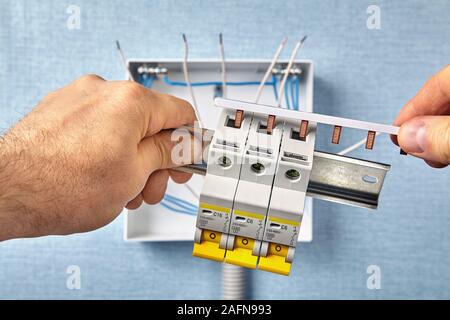 Un tecnico monta un armadio o un centralino in una zona residenziale. Un aggiustatore collega interruttori, chiamato anche fusibili, utilizzando un busb Foto Stock