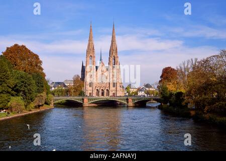 La chiesa di Saint Paul lungo il fiume Ill nel centro di Strasburgo su una soleggiata giornata autunnale, con alberi colorati sulle banche Foto Stock