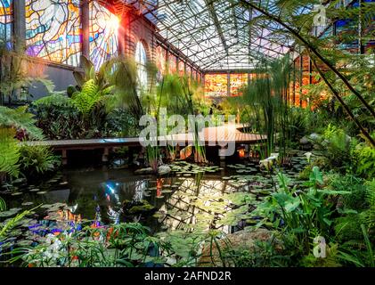 I raggi del sole illuminano uno stagno e le vetrate del Cosmovitral Giardini Botanici, Toluca, Messico. Foto Stock