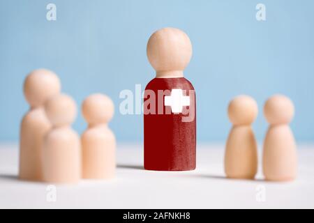 Il concetto di un astratto pediatrico medico accanto a bambini. Statuine di legno su uno sfondo blu. Close up. Foto Stock