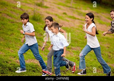 Piccolo gruppo di bambini in esecuzione insieme in natura. Foto Stock