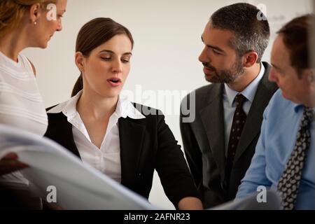 Piccolo gruppo di uomini di affari in un incontro guardando i progetti di un edificio. Foto Stock