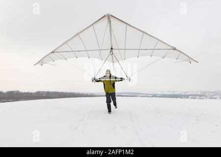 Uomo Felice Tiene vintage deltaplano ala. Parapendio in inverno. Foto Stock