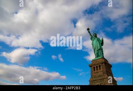 Statua della Libertà isolato sul cielo blu con nuvole bianche nello stato di New York , USA . Dicembre 25, 2018. Vista dal basso Foto Stock