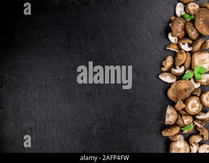 Porzione di materie funghi shiitake su un rustico di lastre di ardesia, il fuoco selettivo di close-up shot Foto Stock