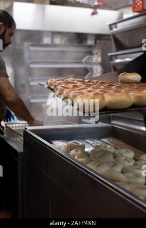 Bagel essendo disposta in corrispondenza di una tradizionale panetteria ebraica in Brick Lane, East London, Regno Unito. Tradizionalmente i bagel sono bolliti brevemente prima che essi sono cotti. Foto Stock