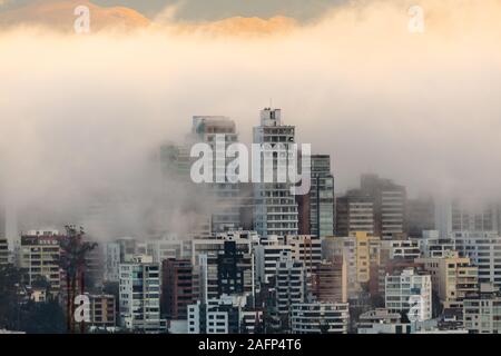 Edifici circondati dalla nebbia alla fine di un caldo pomeriggio nella parte settentrionale della città di Quito Foto Stock