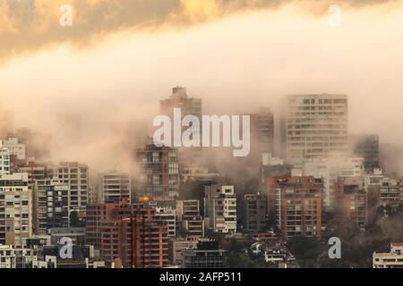 Edifici circondati dalla nebbia alla fine di un caldo pomeriggio nella parte settentrionale della città di Quito Foto Stock