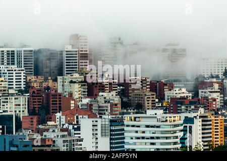 Edifici circondati dalla nebbia alla fine di un caldo pomeriggio nella parte settentrionale della città di Quito Foto Stock