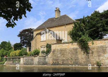 Il fiume Windrush passa davanti a un pittoresco edificio in pietra a Bourton-on-the-River nell'area di Cotswolds nel centro dell'Inghilterra meridionale. Foto Stock