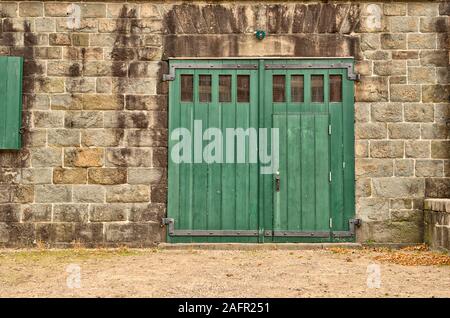 In legno della porta di ingresso di un vecchio edificio. Muro di mattoni su entrambi i lati. Vista frontale. Foto Stock
