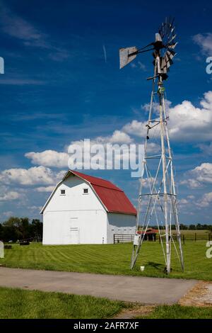 Maggio 17, 2019, Jefferson City, MO USA - granaio di bianco con un tetto rosso e il mulino a vento lungo l'autostrada 100 al di fuori della Città di Jefferson, MO Foto Stock