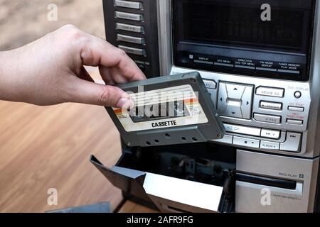 Le donne mettendo mano la cassetta nel vecchio nastro audio player sul banco superiore Sfondo legno Foto Stock