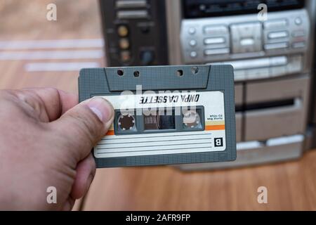 Man mano mettere la cassetta nel vecchio nastro audio player sul banco superiore Sfondo legno Foto Stock