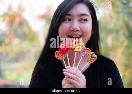 Dolci caramelle forma di cuore pieno di colore in mano alle donne su sfondo sfocato, impostare la caramella di colore arcobaleno lecca-lecca, dono per il giorno di san valentino amore concepton Foto Stock