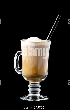 Il caffè con il gelato in un vetro. In vetro vi è un tubo per bere un drink di colore nero. Isolato su sfondo nero. Foto Stock