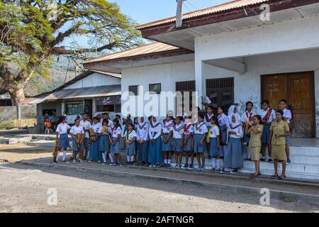 Scuola locale coro di bambini di eseguire all'arrivo di una piccola nave da crociera al porto di Kalabahi, Isola Alor, Indonesia Foto Stock