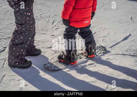 La Madre insegna il figlio lo snowboard. Attività per bambini in inverno. Bambini sport invernali. Stile di vita Foto Stock