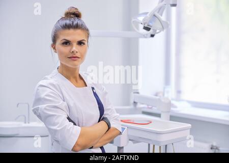 Giovani fiduciosi femmina medico dentista con bracci ripiegati Foto Stock