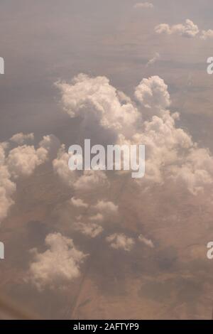 Vista delle nuvole dalla finestra di aeroplano vola ad alta quota che mostra la terra al di sotto di Foto Stock