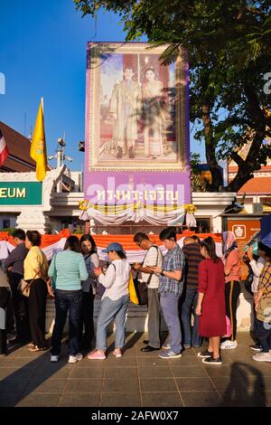 I visitatori di fronte al Museo Nazionale di Bangkok, Thailandia e sotto un ritratto del Royal Thai giovane, in attesa del museo di apertura del mattino Foto Stock