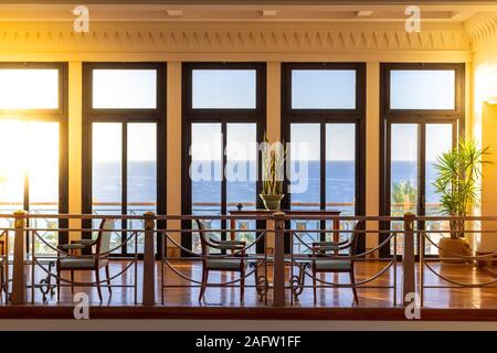 Hall con cinque grandi finestre con vista sul mare. Spazioso e luminoso in vecchio stile camera con finestre in legno. I raggi del sole inondare la camera con vista mare Foto Stock