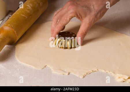 Il processo di cottura di pasticcini. Chiudere fino a mani la cottura in casa sul tavolo da cucina Foto Stock