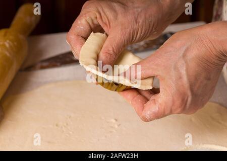 Il processo di cottura di pasticcini. Chiudere fino a mani la cottura in casa sul tavolo da cucina Foto Stock