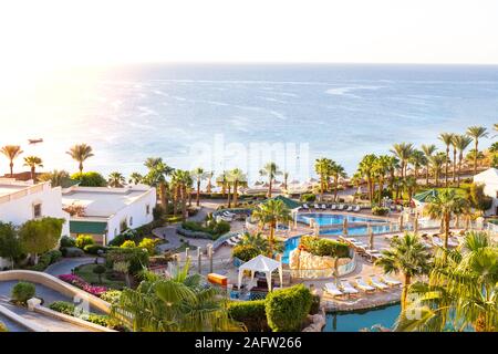 Hotel lussuosi giardini. Architettura paesaggistica e piscina con lettini da mare che si affaccia sul mare. Una vegetazione lussureggiante e alberi tropicali. Alta classe località balneare. Foto Stock