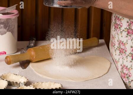 Preparazione di pasta di pane. Panificio, farina è versata, battenti farina. battendo le mani e spolverata di farina sull impasto sul tavolo Foto Stock