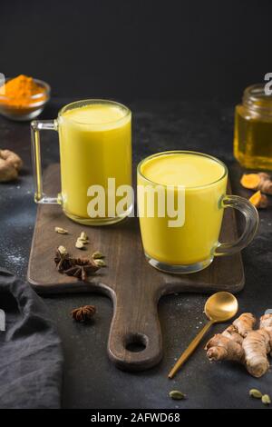 2 tazza di ayurvedic golden curcuma latte con curcuma in polvere e anice stella sul nero. Close up. Sana bevanda indiana. Orientamento verticale. Foto Stock