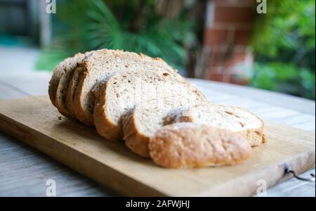 Fette di salutari e freschi di pasta acida pane su un tagliere di legno Foto Stock
