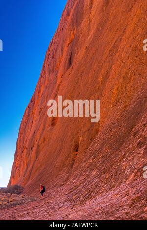 Un maschio di turista è sopraffatte dalla dimensione delle pareti sul Walpa Gorge a piedi attraverso il Olgas. Questa zona è una parte iconica dell'outback australiano. Foto Stock