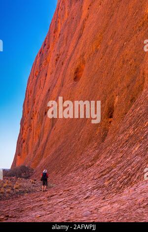 Un maschio di turista è sopraffatte dalla dimensione delle pareti sul Walpa Gorge a piedi attraverso il Olgas. Questa zona è una parte iconica dell'outback australiano. Foto Stock