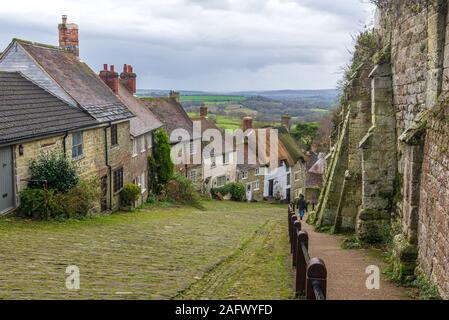 Ripida strada di ciottoli con cottage con il tetto di paglia, Gold Hill, Shaftesbury, Dorset, Regno Unito nel mese di dicembre Foto Stock