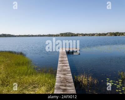 Percorso in legno sull'acqua con un cielo blu lo sfondo Foto Stock