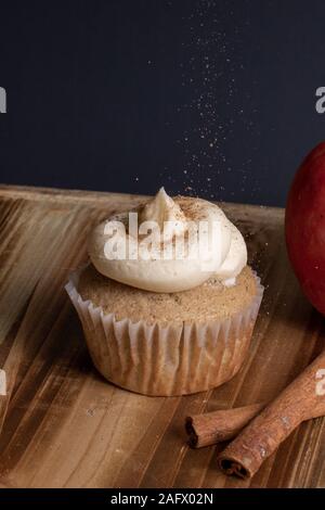 Colpo verticale di un cupcake con glassa mentre spruzzando il polvere di caffè sulla parte superiore Foto Stock